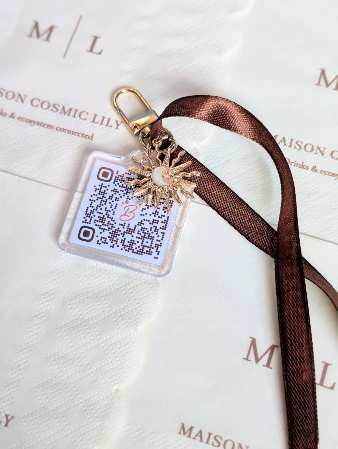 Porte-clé acrylique avec QR code et breloque soleil, posé sur une serviette imprimée